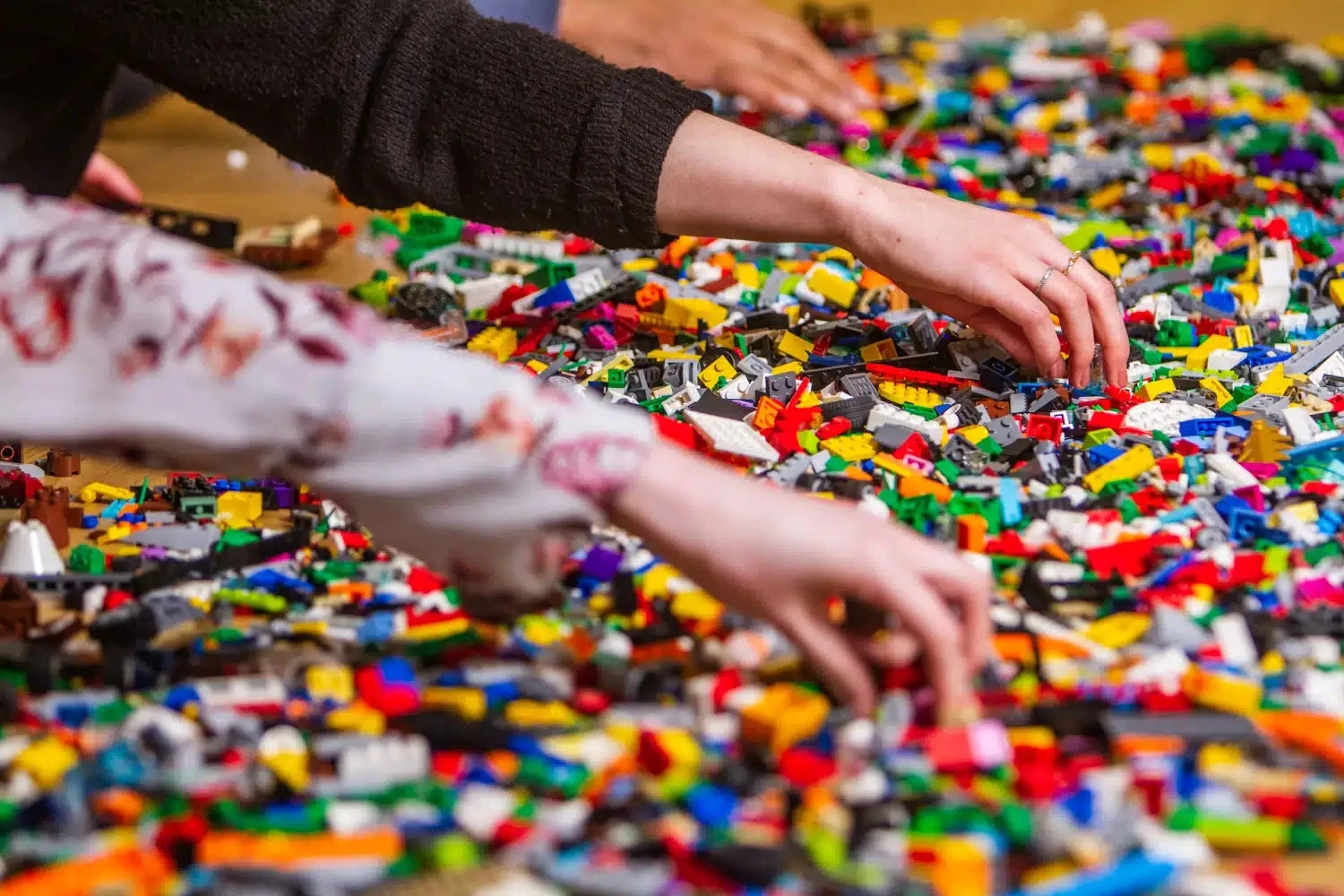 Hands reaching into piles of lego.